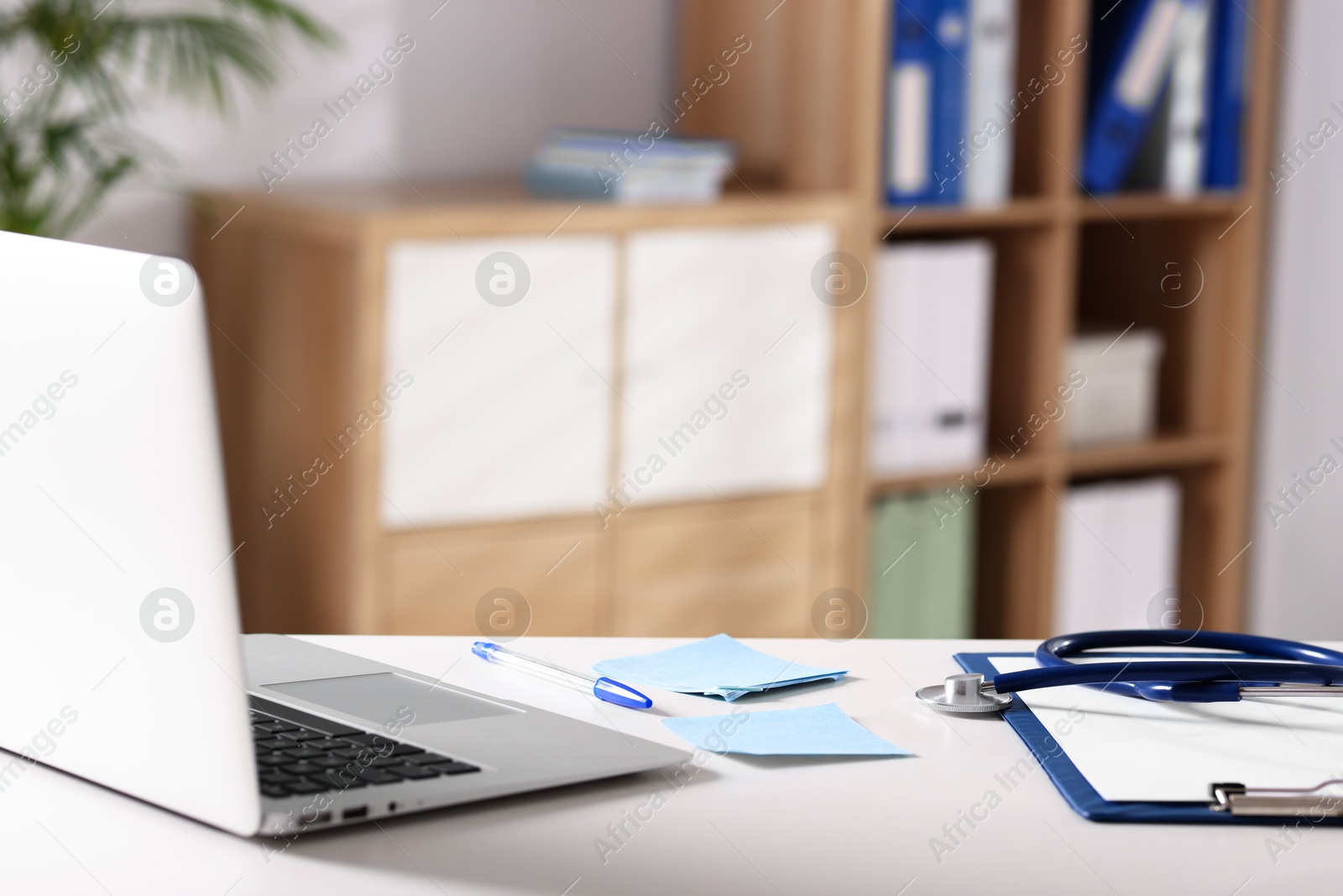 Photo of Doctor's workplace. Laptop, stationery and stethoscope on white table in medical office, space for text