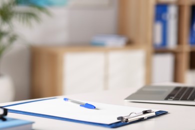 Photo of Doctor's workplace. Clipboard and pen on white table in medical office, closeup. Space for text