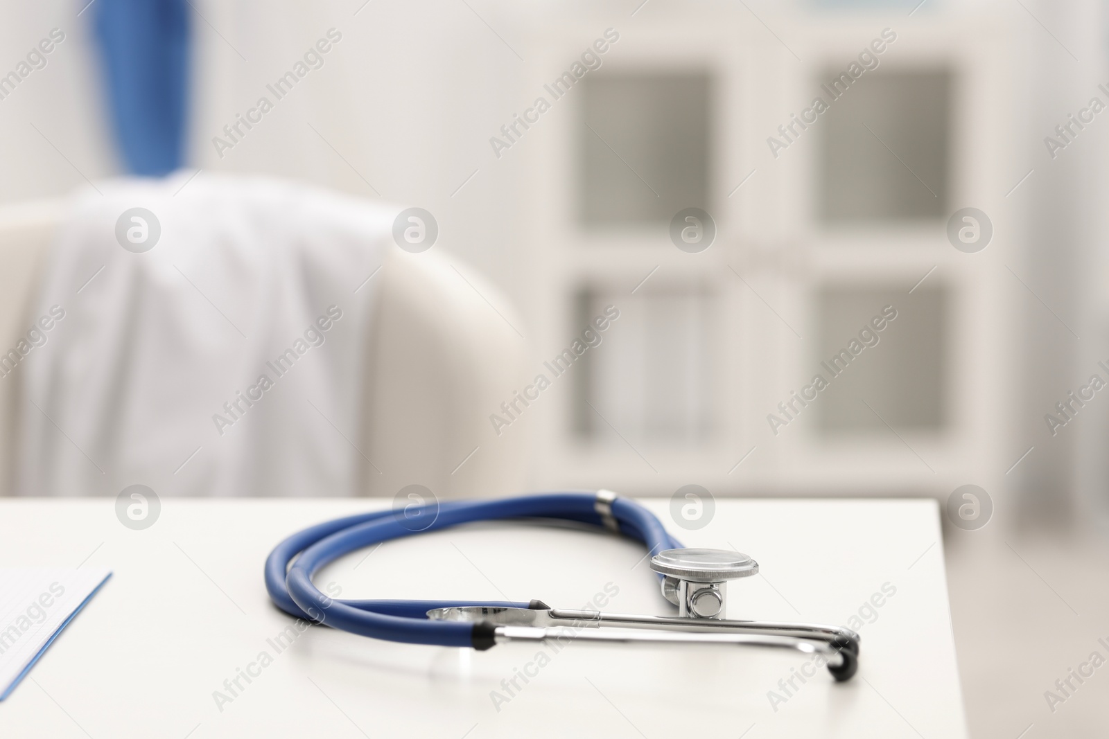 Doctor's workplace. Stethoscope on white table in medical office, closeup. Space for text Photo of Doctor's workplace. Stethoscope on white table in medical office, closeup. Space for text