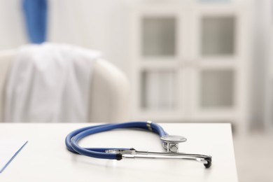 Photo of Doctor's workplace. Stethoscope on white table in medical office, closeup. Space for text