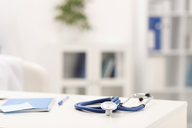 Photo of Doctor's workplace. Stethoscope and stationery on white table in medical office, closeup. Space for text