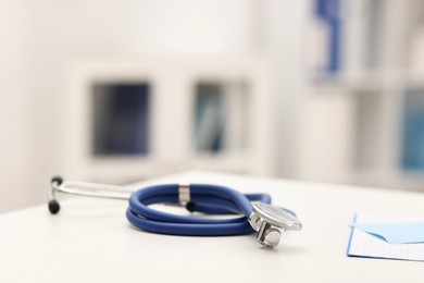 Photo of Doctor's workplace. Stethoscope on white table in medical office, closeup. Space for text