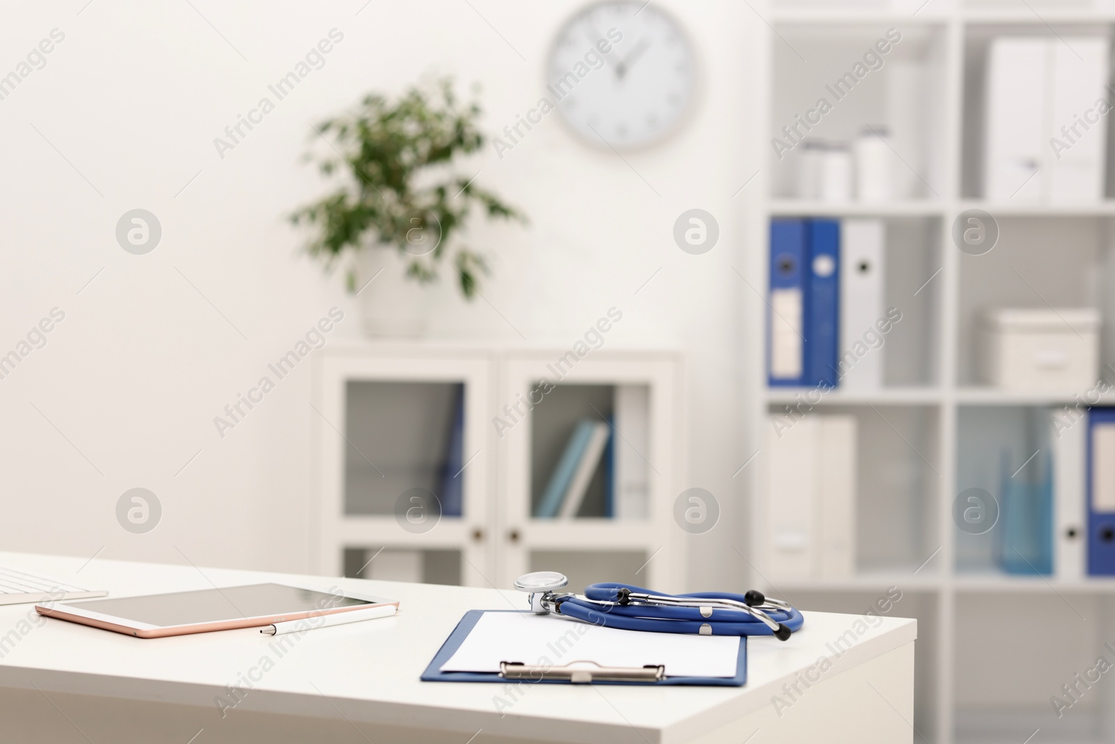 Doctor's workplace. Clipboard, stethoscope and tablet on white table in medical office Photo of Doctor's workplace. Clipboard, stethoscope and tablet on white table in medical office