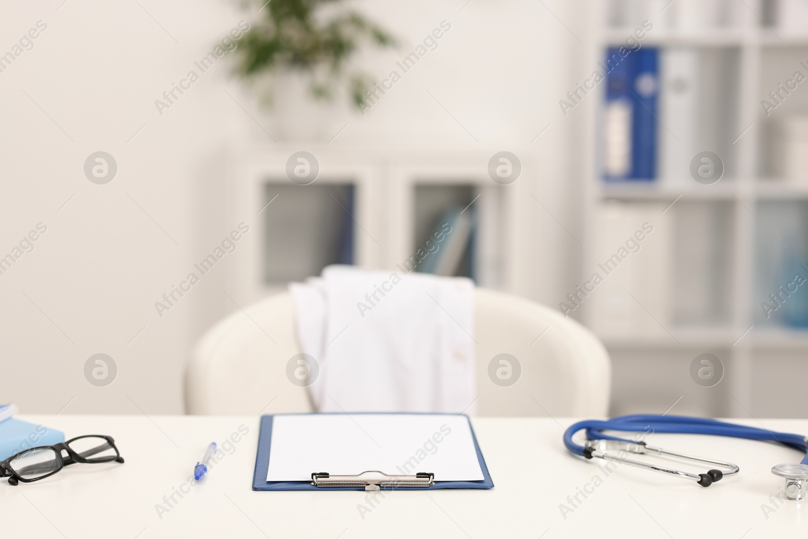Doctor's workplace. Clipboard, other stationery, stethoscope and glasses on white table in medical office Photo of Doctor's workplace. Clipboard, other stationery, stethoscope and glasses on white table in medical office