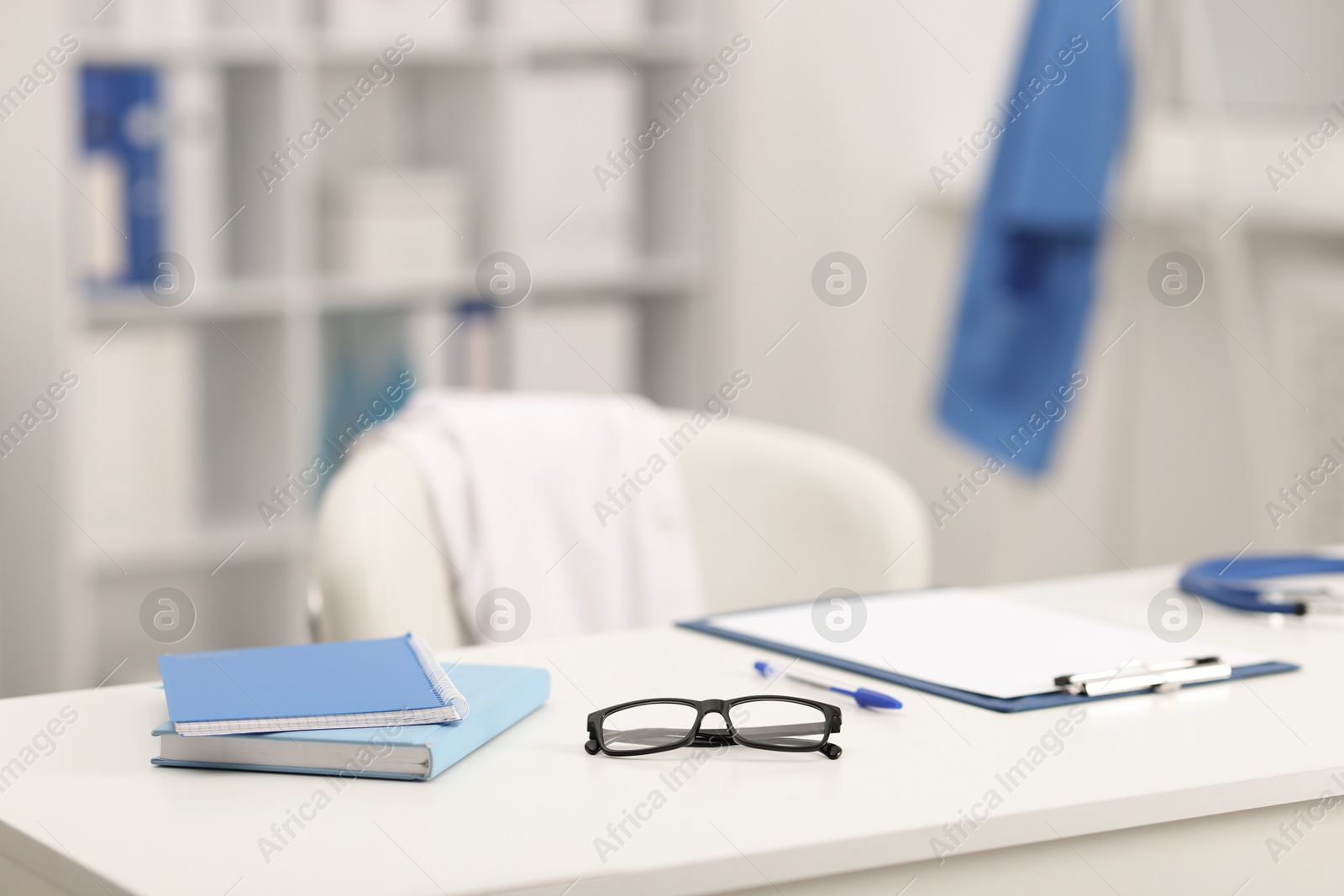 Doctor's workplace. Clipboard, other stationery and glasses on white table in medical office Photo of Doctor's workplace. Clipboard, other stationery and glasses on white table in medical office