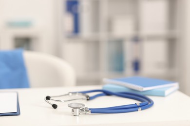 Photo of Doctor's workplace. Stethoscope and notebooks on white table in medical office, closeup. Space for text