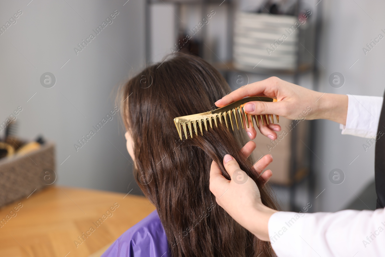 Hairdresser combing girl's hair in salon, closeup Photo of Hairdresser combing girl's hair in salon, closeup