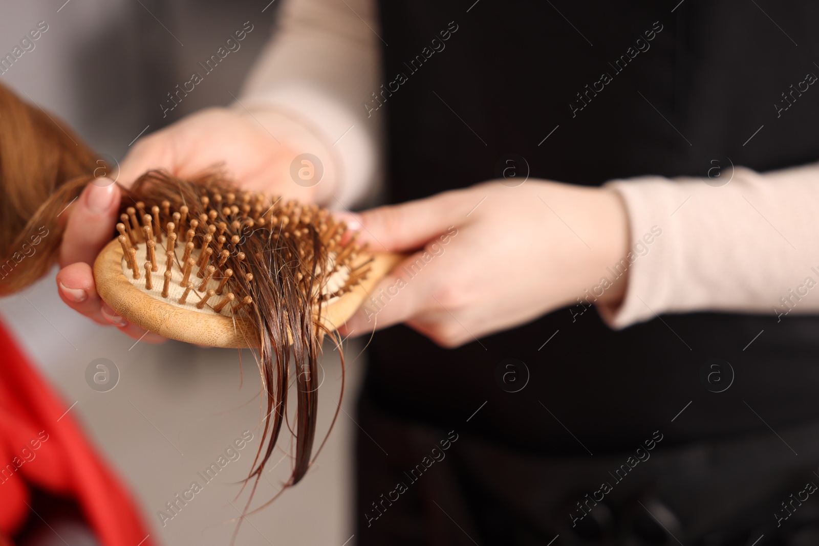 Photo of Hairdresser brushing girl's hair in salon, closeup