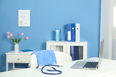 Photo of Doctor's workplace. Laptop and stethoscope on white table in medical office