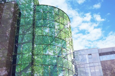 Image of Modern buildings and lush trees against blue sky, double exposure. Low angle view