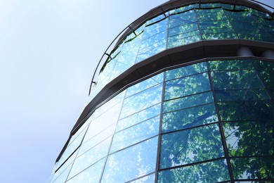 Image of Modern skyscraper and lush tree against blue sky, double exposure. Low angle view