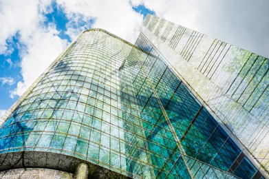 Image of Modern skyscrapers and lush trees against blue sky, double exposure. Low angle view