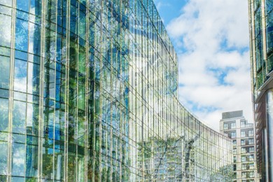 Image of Modern buildings and lush trees against blue sky, double exposure