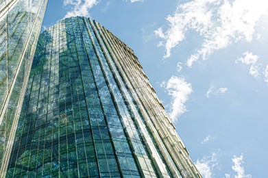 Image of Modern skyscrapers and lush trees against blue sky, double exposure. Low angle view