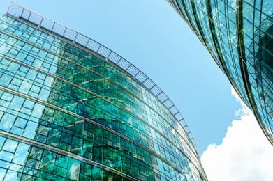 Image of Modern buildings and green trees against blue sky, double exposure. Low angle view