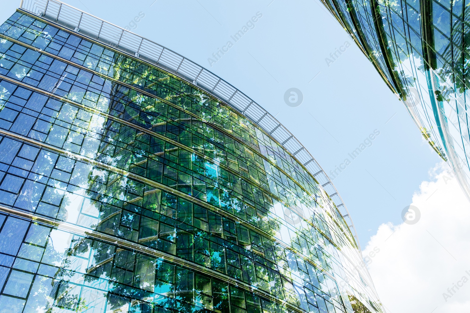 Modern buildings and green trees against blue sky, double exposure. Low angle view Image of Modern buildings and green trees against blue sky, double exposure. Low angle view