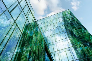 Image of Modern building and lush trees against blue sky, double exposure. Low angle view