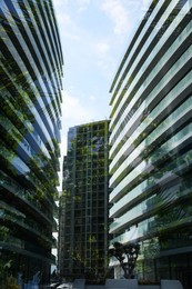Image of Modern buildings and lush trees against blue sky, double exposure. Low angle view