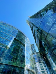 Image of Modern skyscrapers and lush trees against blue sky, double exposure. Low angle view
