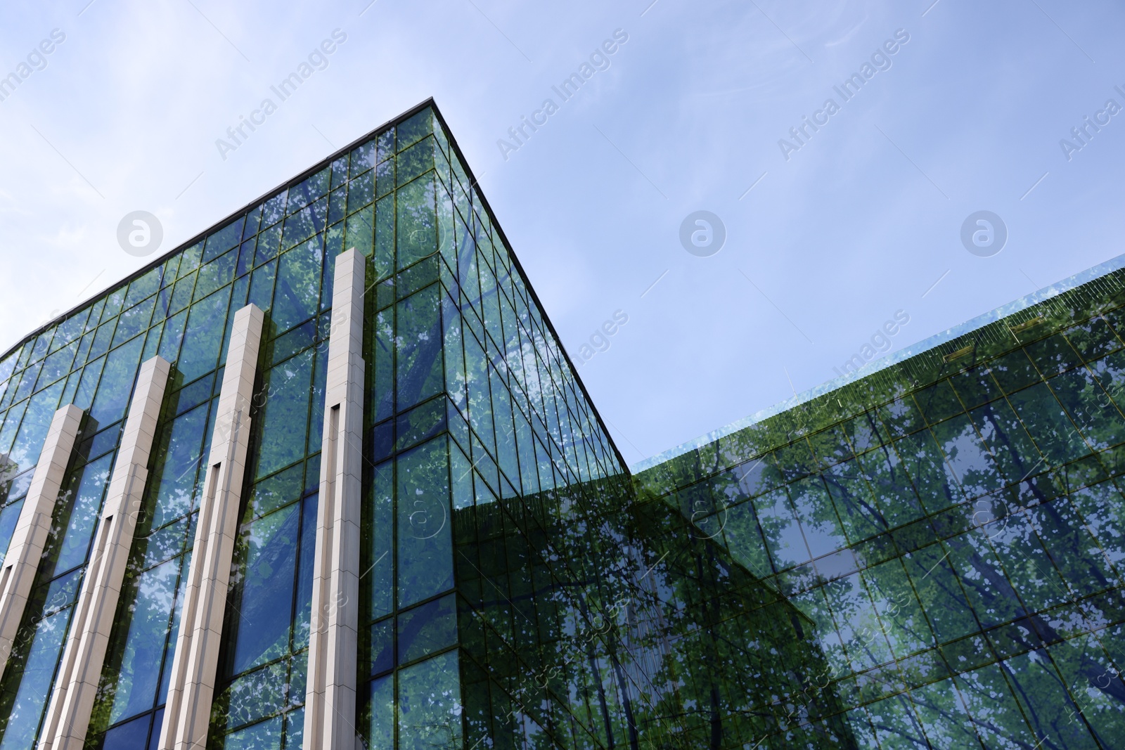 Modern building and lush trees against blue sky, double exposure. Low angle view Image of Modern building and lush trees against blue sky, double exposure. Low angle view