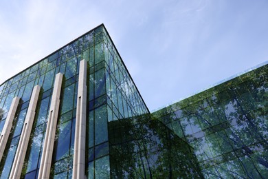 Image of Modern building and lush trees against blue sky, double exposure. Low angle view