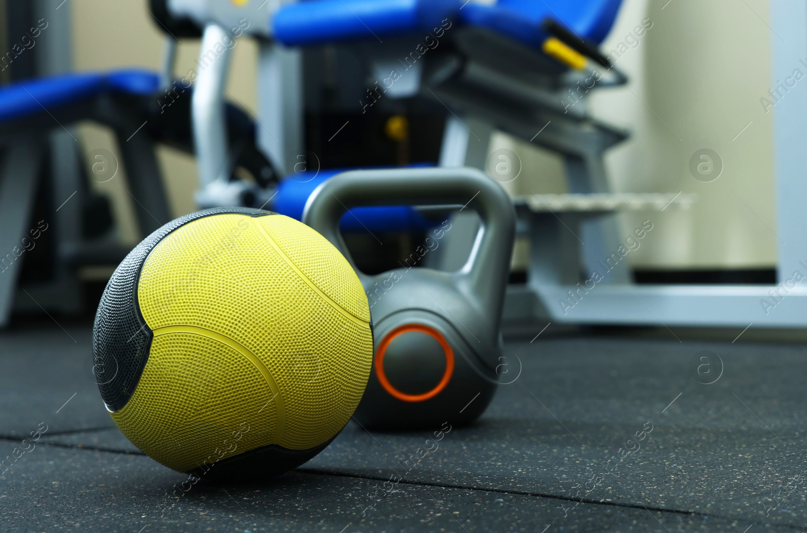 Yellow medicine ball and kettlebell on floor in gym, space for text Photo of Yellow medicine ball and kettlebell on floor in gym, space for text