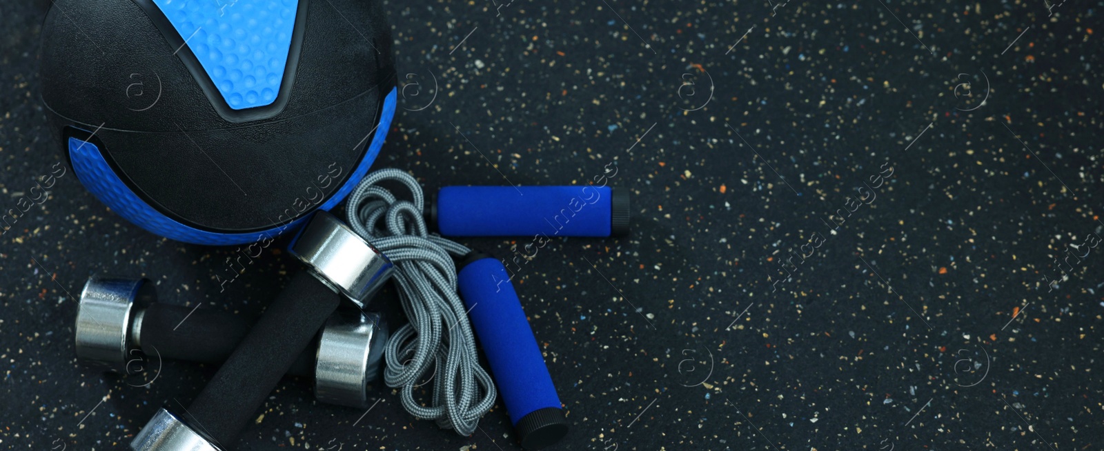 Blue medicine ball, dumbbells and skipping rope on floor, space for text Photo of Blue medicine ball, dumbbells and skipping rope on floor, space for text