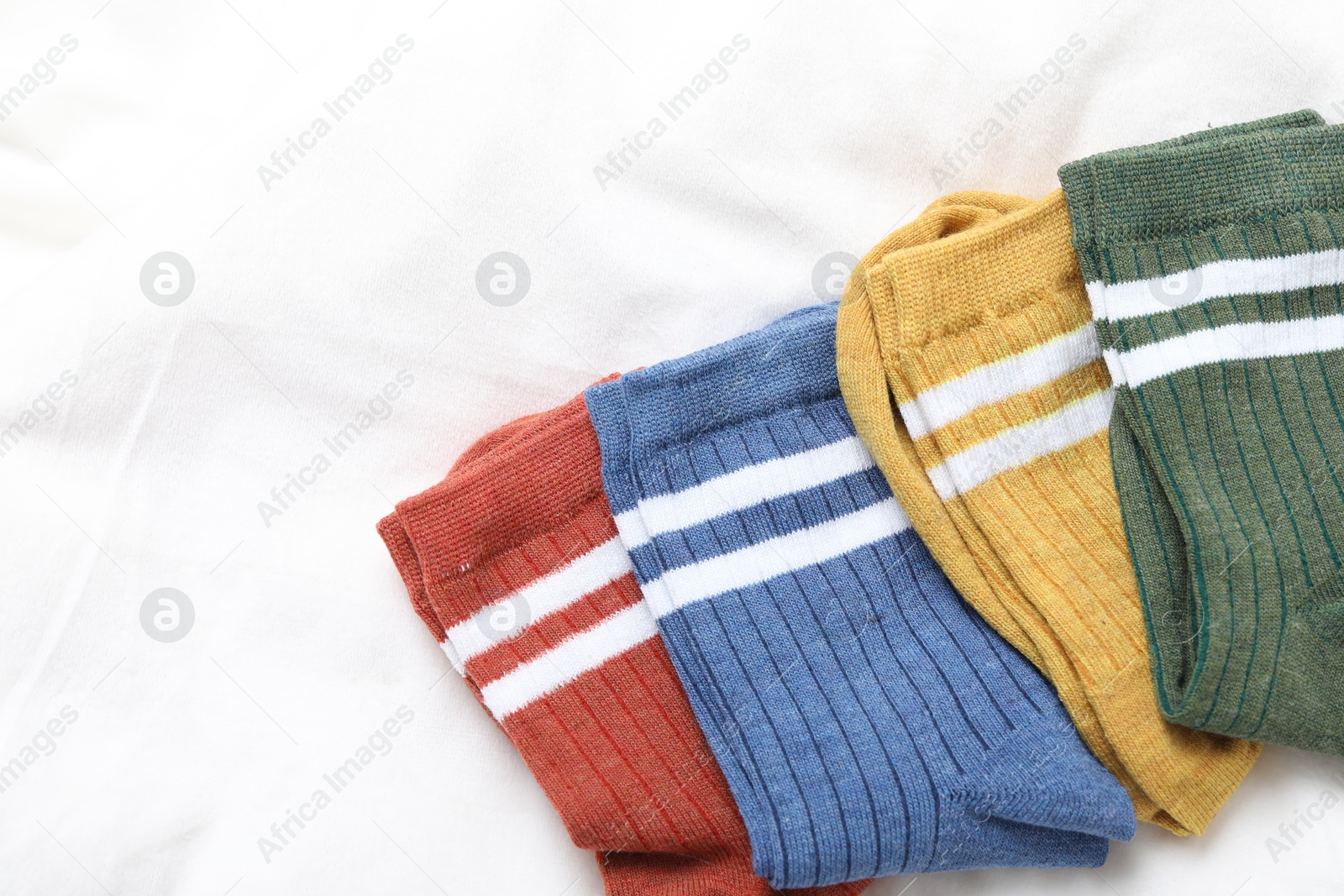 Different soft socks on white blanket, top view. Space for text Photo of Different soft socks on white blanket, top view. Space for text