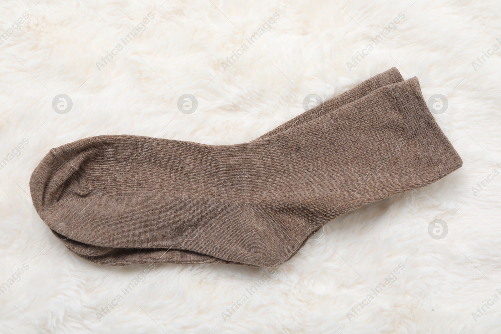 Pair of soft socks on white faux fur, top view Photo of Pair of soft socks on white faux fur, top view