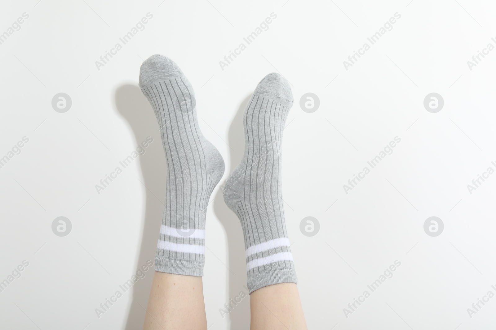 Woman in grey socks on light background, closeup Photo of Woman in grey socks on light background, closeup