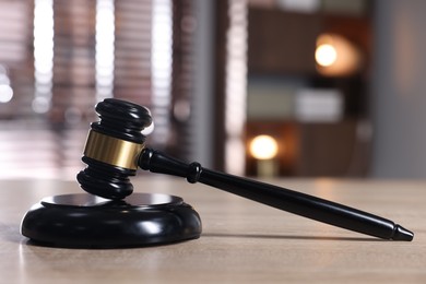 Photo of Judge's gavel and sound block on wooden table against blurred background, closeup