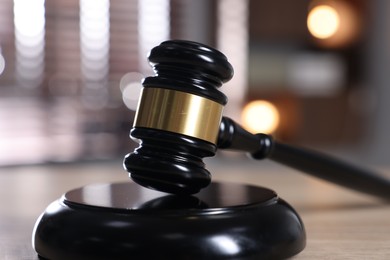 Photo of Judge's gavel and sound block on wooden table against blurred background, closeup