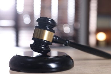 Photo of Judge's gavel and sound block on wooden table against blurred background, closeup