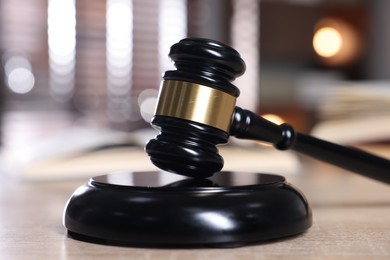 Photo of Judge's gavel and sound block on wooden table against blurred background, closeup
