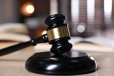 Photo of Judge's gavel and sound block on wooden table against blurred background, closeup