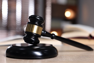 Photo of Judge's gavel and sound block on wooden table against blurred background, closeup