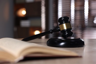 Photo of Judge's gavel, sound block and book on table against blurred background, selective focus