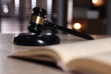 Photo of Judge's gavel, sound block and book on table against blurred background, selective focus