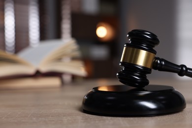 Photo of Judge's gavel and sound block on wooden table against blurred background, closeup. Space for text
