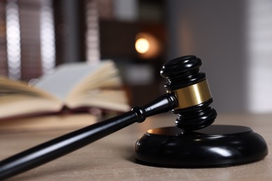 Photo of Judge's gavel and sound block on wooden table against blurred background, closeup