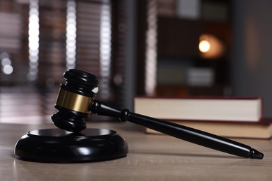 Photo of Judge's gavel and sound block on wooden table against blurred background, closeup