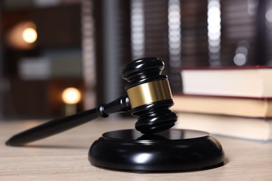 Photo of Judge's gavel and sound block on wooden table against blurred background, closeup