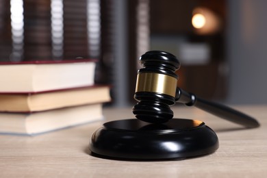 Photo of Judge's gavel and sound block on wooden table against blurred background, closeup
