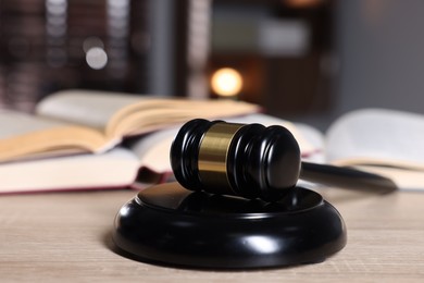 Photo of Judge's gavel and sound block on wooden table against blurred background, closeup
