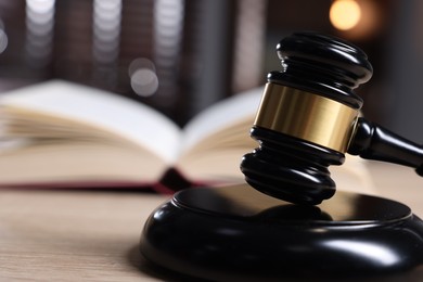 Photo of Judge's gavel and sound block on wooden table against blurred background, closeup