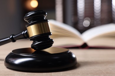 Photo of Judge's gavel and sound block on wooden table against blurred background, closeup