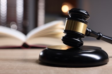 Photo of Judge's gavel and sound block on wooden table against blurred background, closeup