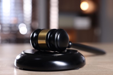 Photo of Judge's gavel and sound block on wooden table against blurred background, closeup