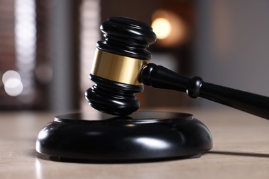 Photo of Judge's gavel and sound block on wooden table against blurred background, closeup