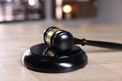 Photo of Judge's gavel and sound block on wooden table against blurred background, closeup